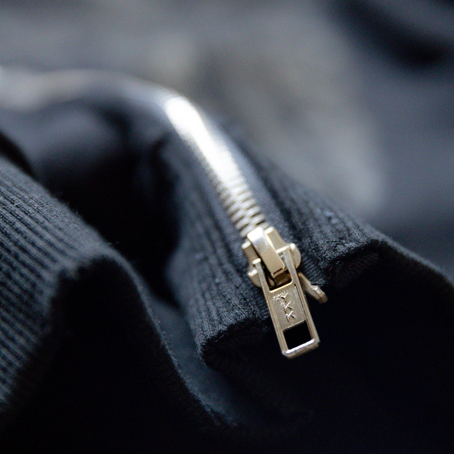 Close-up of a ykk zipper on a dark fabric background