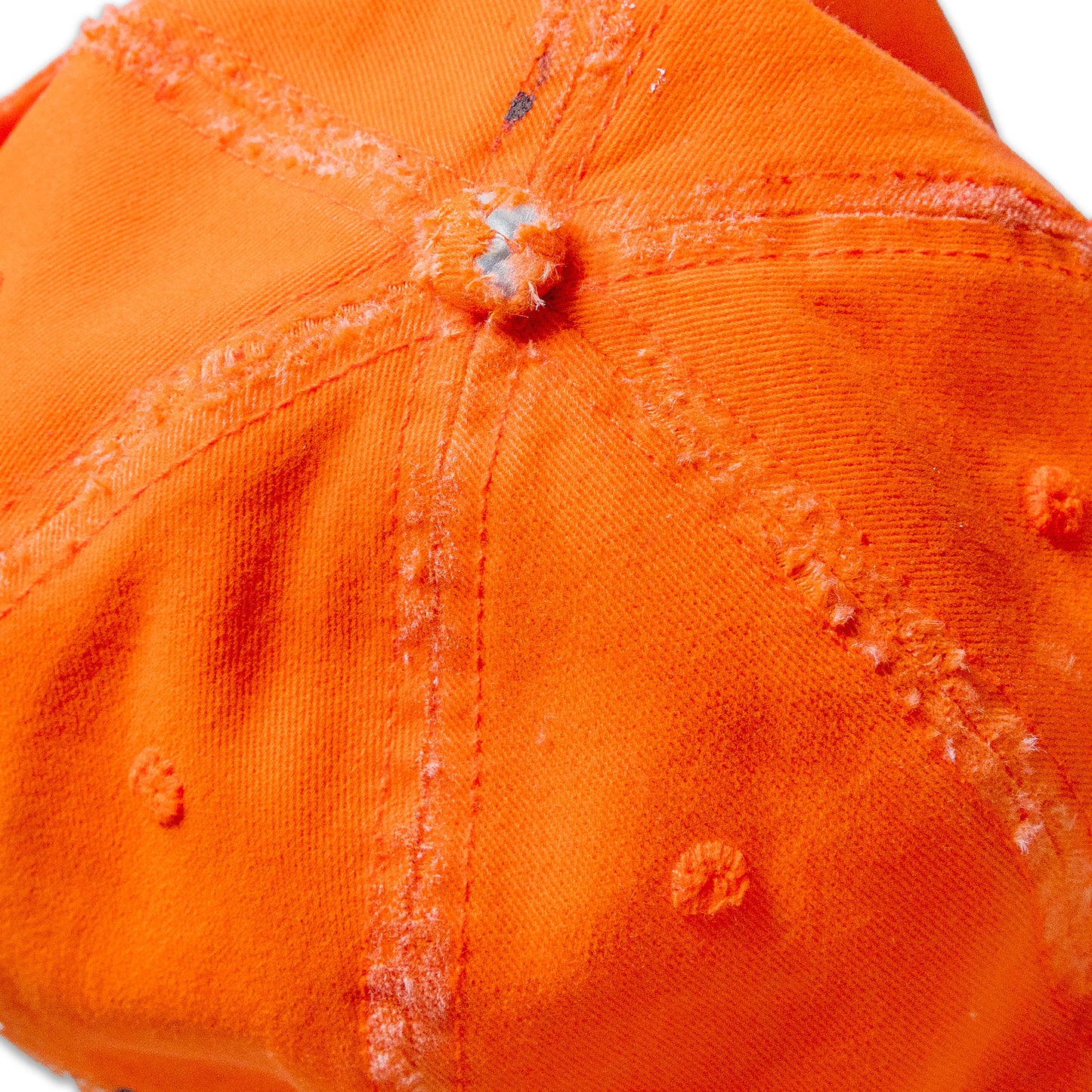 Close-up of an orange cap with visible wear and tear on a white background