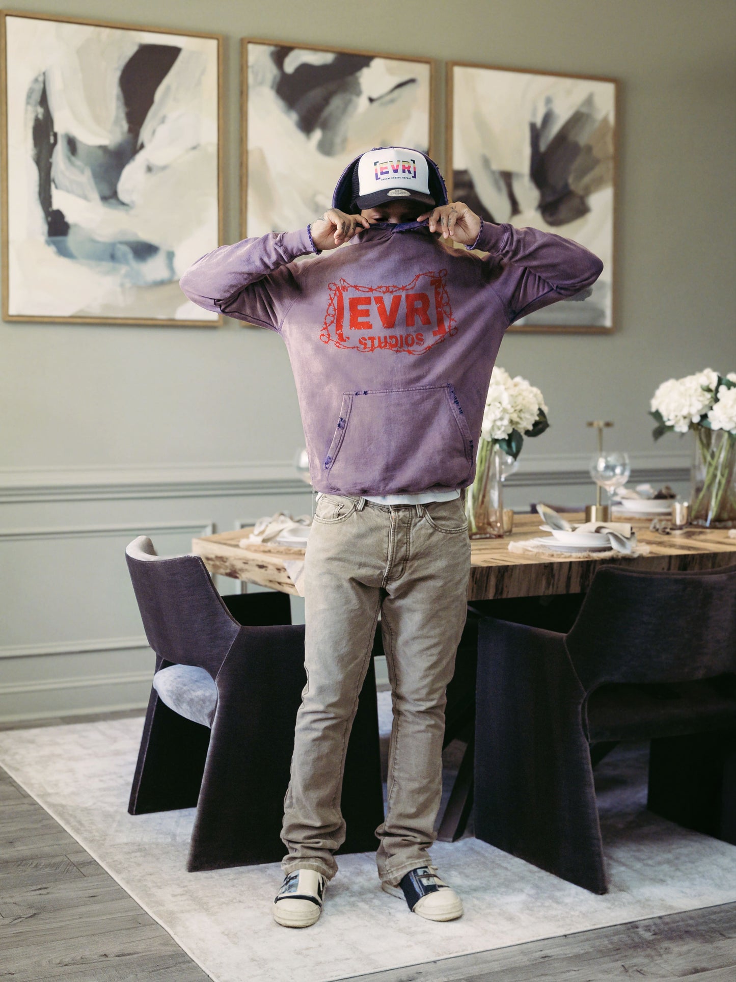 Person wearing a purple sweatshirt with 'EVEV' branding in a dining room setting.