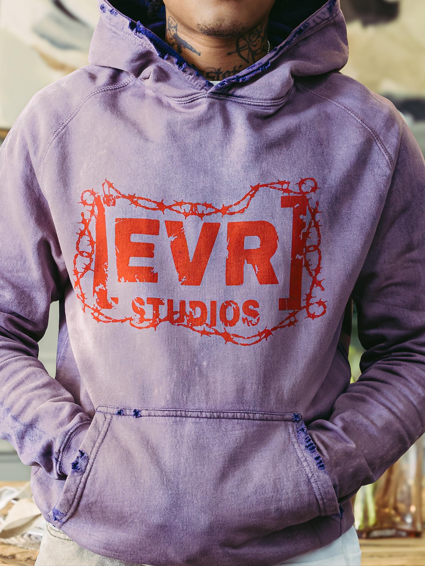 Person wearing a purple hoodie with 'EVR STUDIOS' logo in red