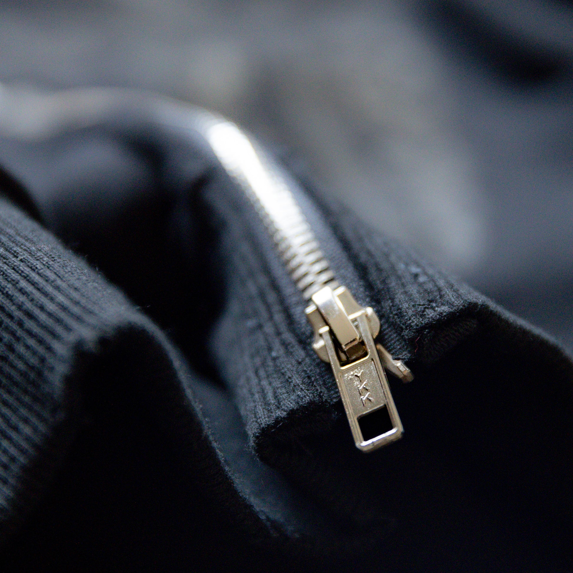Close-up of a ykk zipper on a dark fabric background