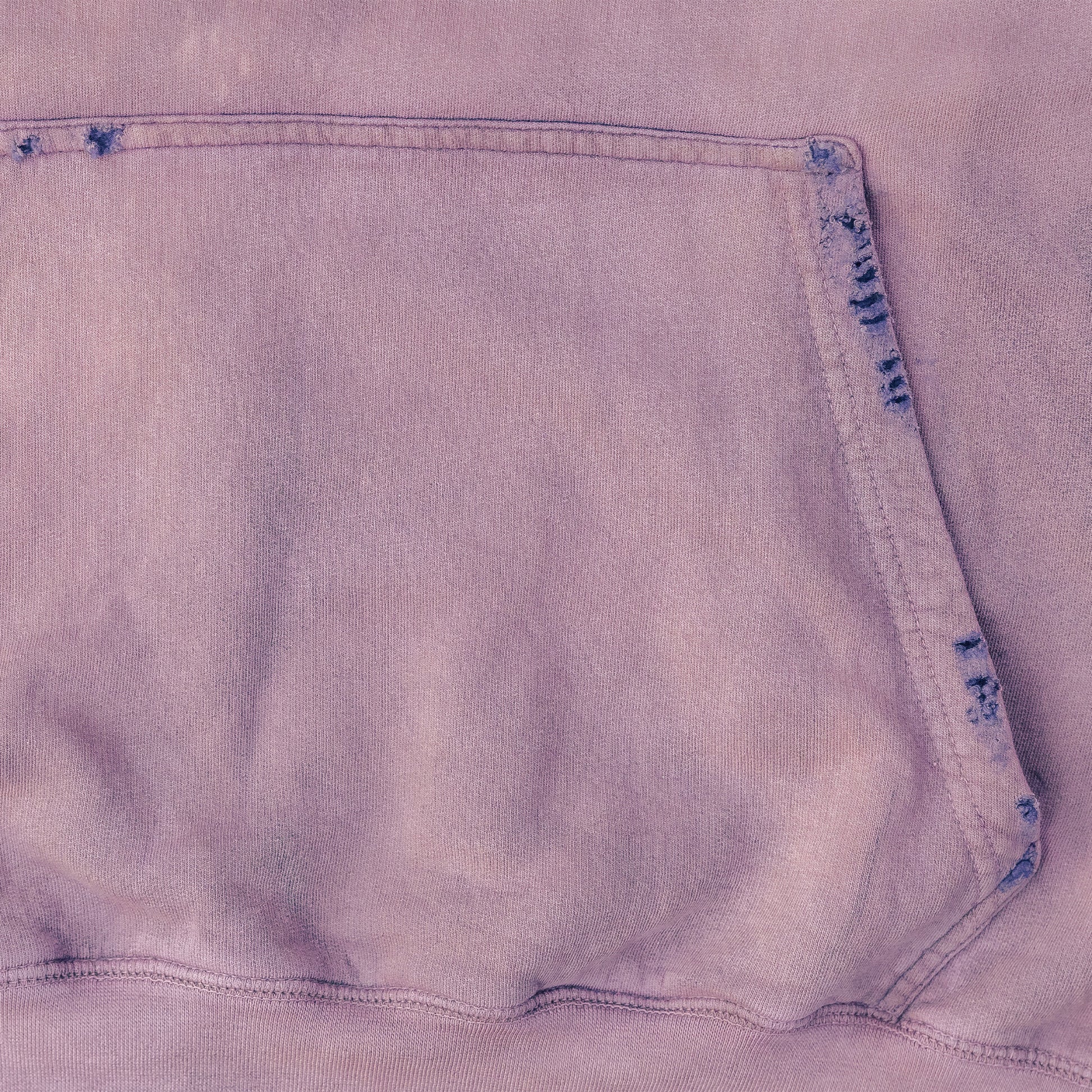 Close-up of a light purple hoodie fabric with a pocket detail