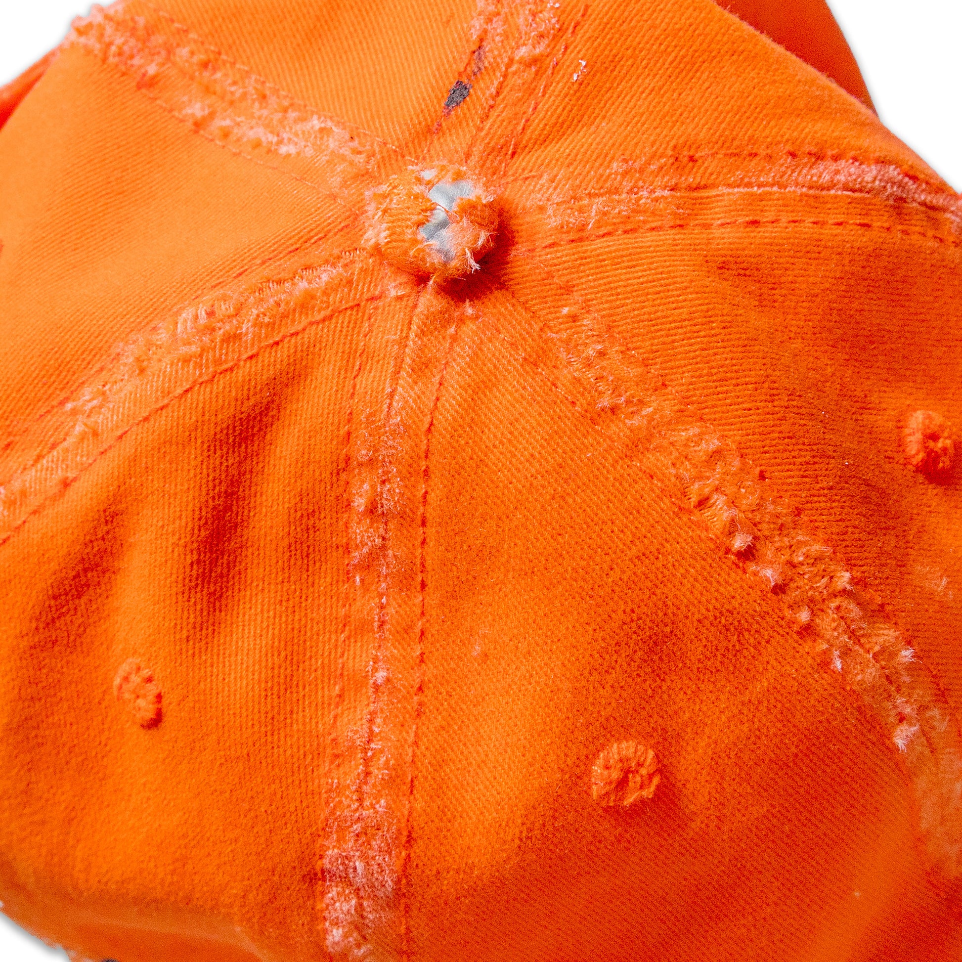 Close-up of an orange cap with visible wear and tear on a white background