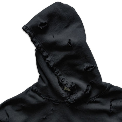 Black hooded garment with frayed edges on a white background