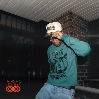 Person wearing a teal sweatshirt with 'Elan Vers Revolution' text, sitting against a dark background.