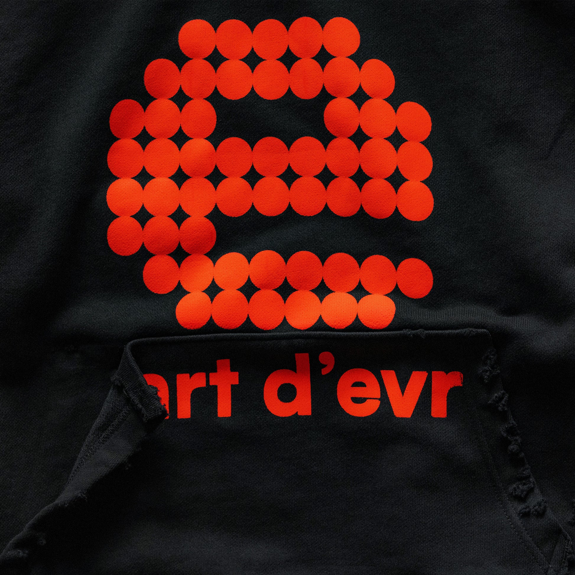 Black hoodie with orange circular pattern and 'l'art d'evr' text on a dark background